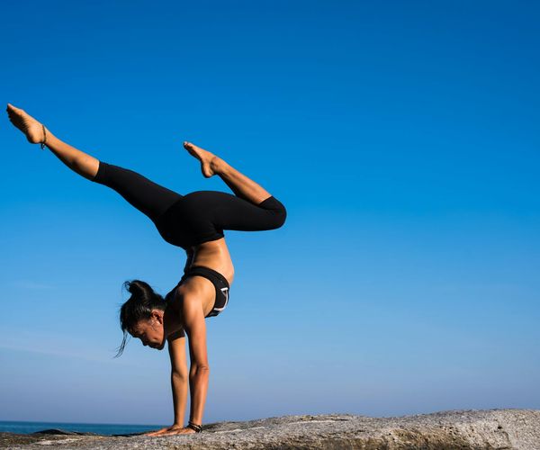 Person maintaining a difficult balance yoga pose outdoors.